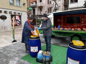 Campagna di sensibilizzazione al mercato settimanale di Grottammare. Un cittadino e una cittadina versano olio vegetale esausto in un contenitore Olivia.